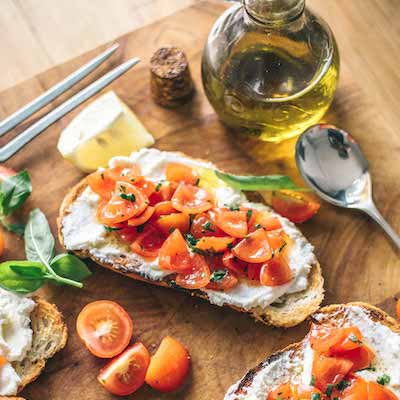 Fresh bread with tomatoes, cheese and olive oil on a wooden table