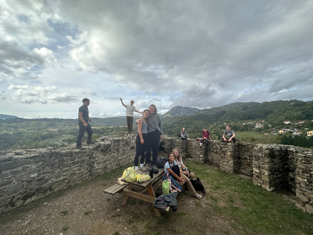 students in a group photo looking out and on picnic bench