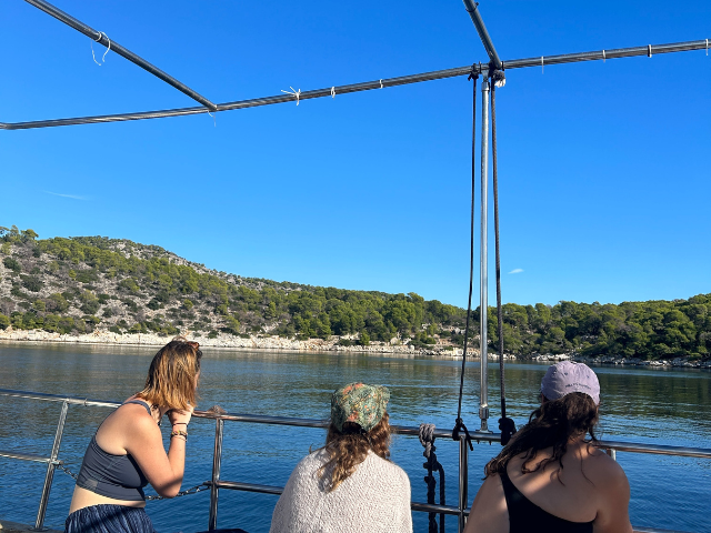students on boat looking at horizon line in greece