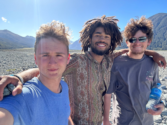 three students arms wrapped mountain background