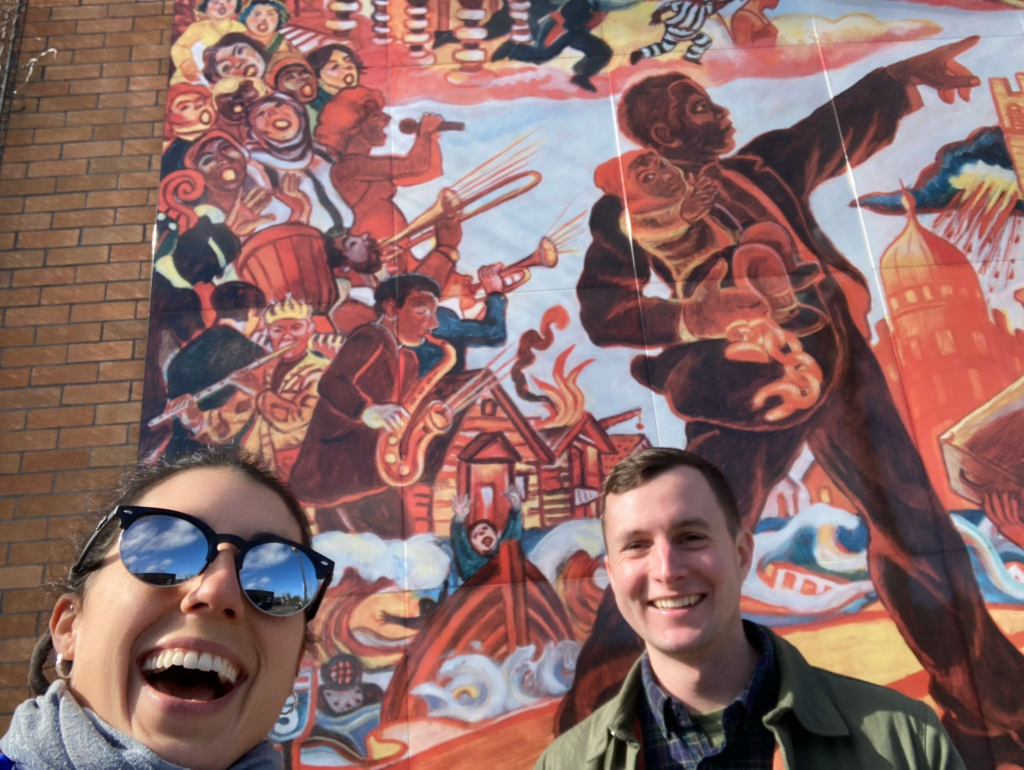Two people in front of a mural