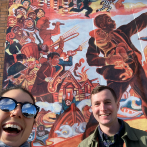 Two people in front of a mural